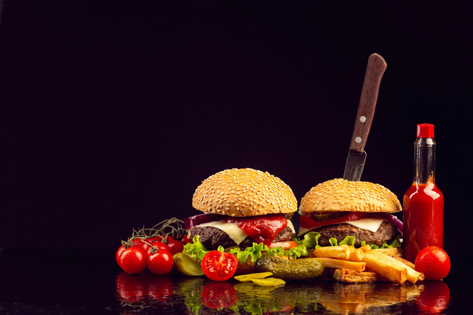 Burgers and fries arranged on a dark tabletop