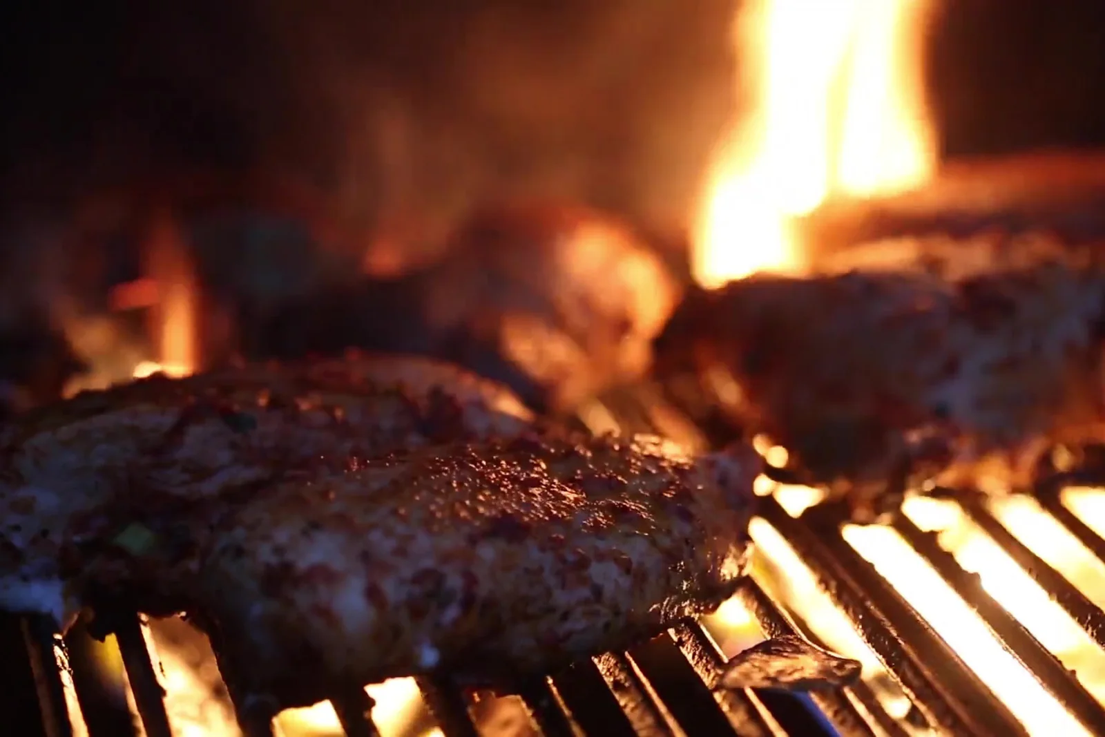 Steaks cooking over an open flame grill
